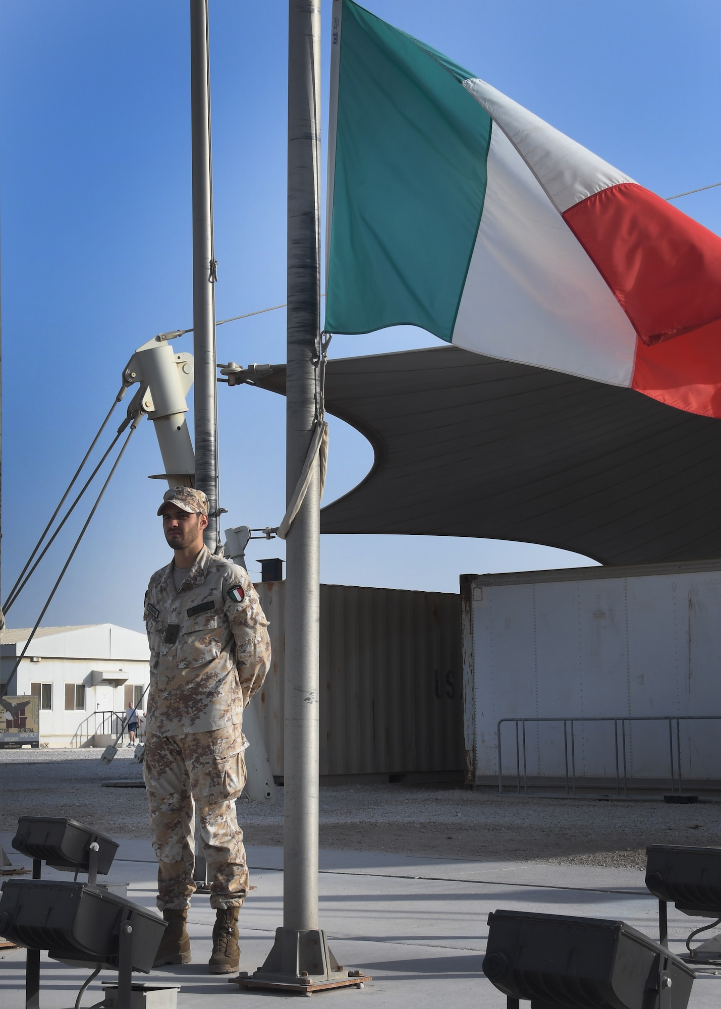 1st Lt. Alberto Vitale of the Italian Detachment at the Combined Air Operations Center stands with the Italian flag at Al Udeid Air Base, Qatar, Nov. 4, 2016. The Italian flag was lowered and then raised during a ceremony for Italian Armed Forces Day, celebrating the allied victory of World War I and commemorating the lives of all those who served. (U.S. Air Force photo by Senior Airman Miles Wilson)