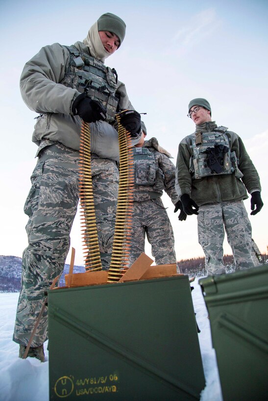 Air Force Airman 1st Class Tyler Parrish, left, breaks off a strip of 7.62 x 51mm ammunition before participating in M240B machine gun live-fire training at Grezelka range, Joint Base Elmendorf-Richardson, Alaska, Oct. 27, 2016. Parrish is an installation entry controller assigned to the 673rd Security Forces Squadron. Air Force photo by Alejandro Pena