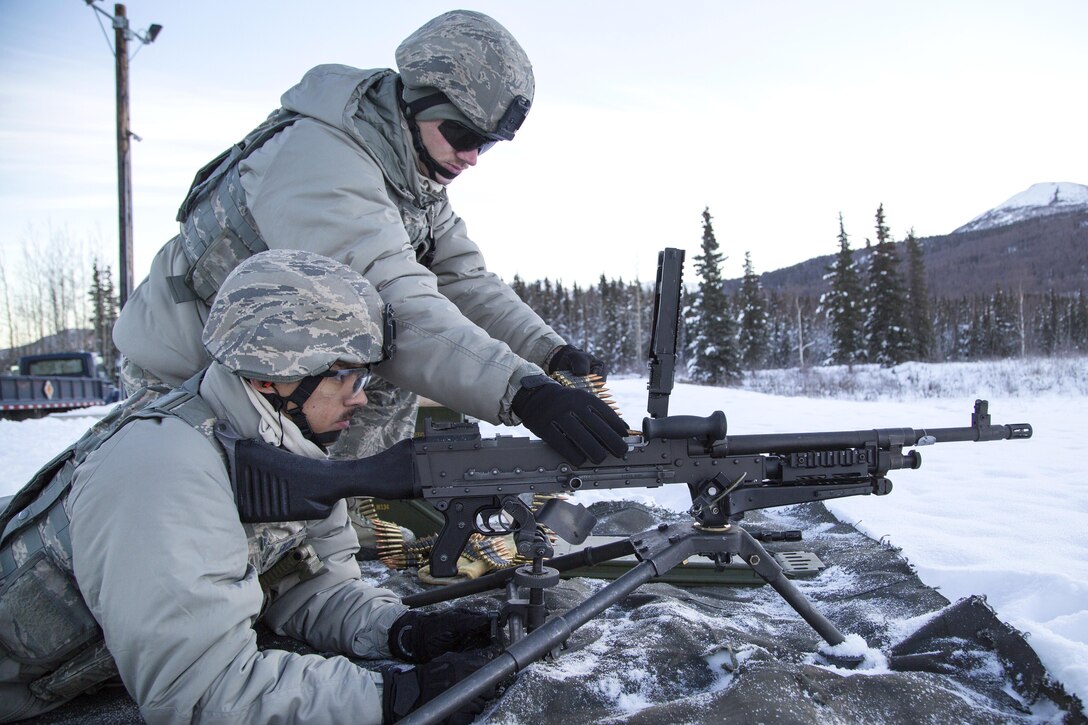 Air Force Airmen 1st Class Tyler Parrish, top, and John Smith load a M240B machine gun during live-fire training at Grezelka range, Joint Base Elmendorf-Richardson, Alaska, Oct. 27, 2016. Parrish and Smith are installation entry controllers assigned to the 673rd Security Forces Squadron. Air Force photo by Alejandro Pena