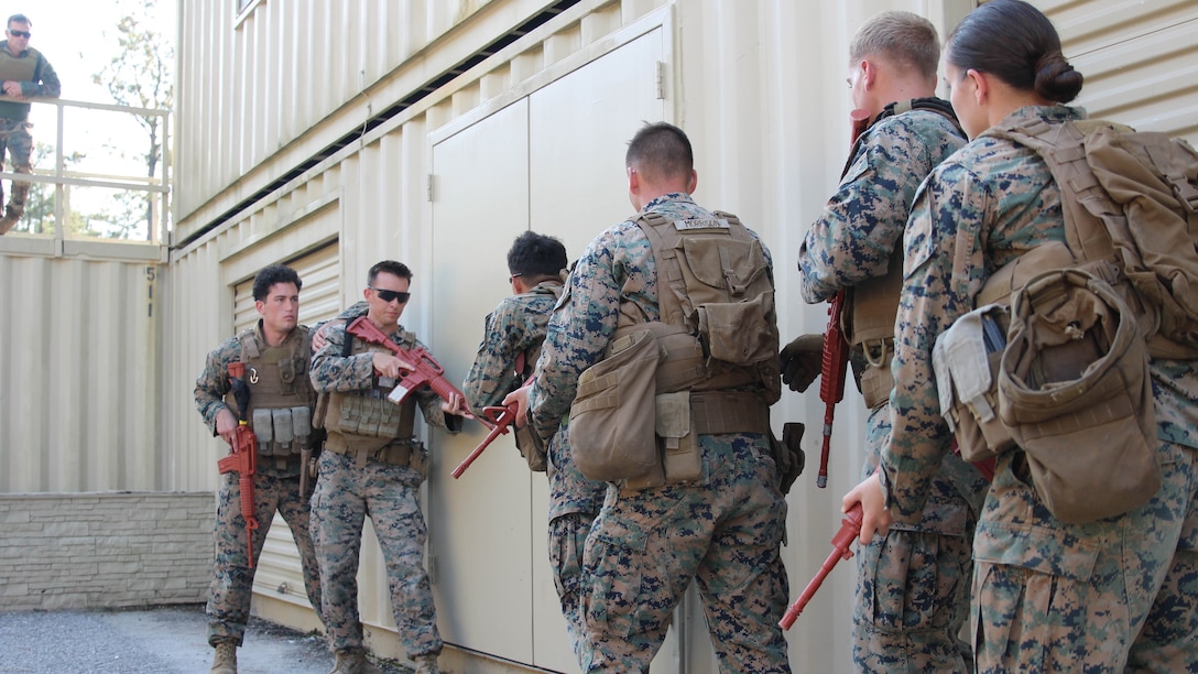 Military policemen from the 24th Marine Expeditionary Unit's law enforcement detachment prepare to forcibly enter a building as their instructor from Marine Corps Forces, Special Operations Command watches on, Nov. 2, 2016. The two groups of Marines were training to develop the urban patrolling and combat skills of the law enforcement detachment as part of their Realistic Urban Training exercise. The group served as a notional partner nation force on which the Marine Raiders refined their coaching and mentoring skills.