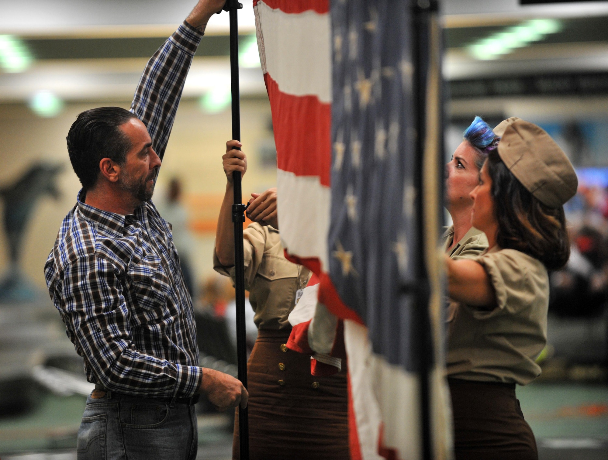 Volunteers set up a flag used as a back drop for photos during a homecoming event hosted by the Honor Flight of West Central Florida at the St. Pete-Clearwater International Airport Nov. 1, 2016. After each veteran made their way through the crowd of people they were given the choice to take a photo with their guardian.