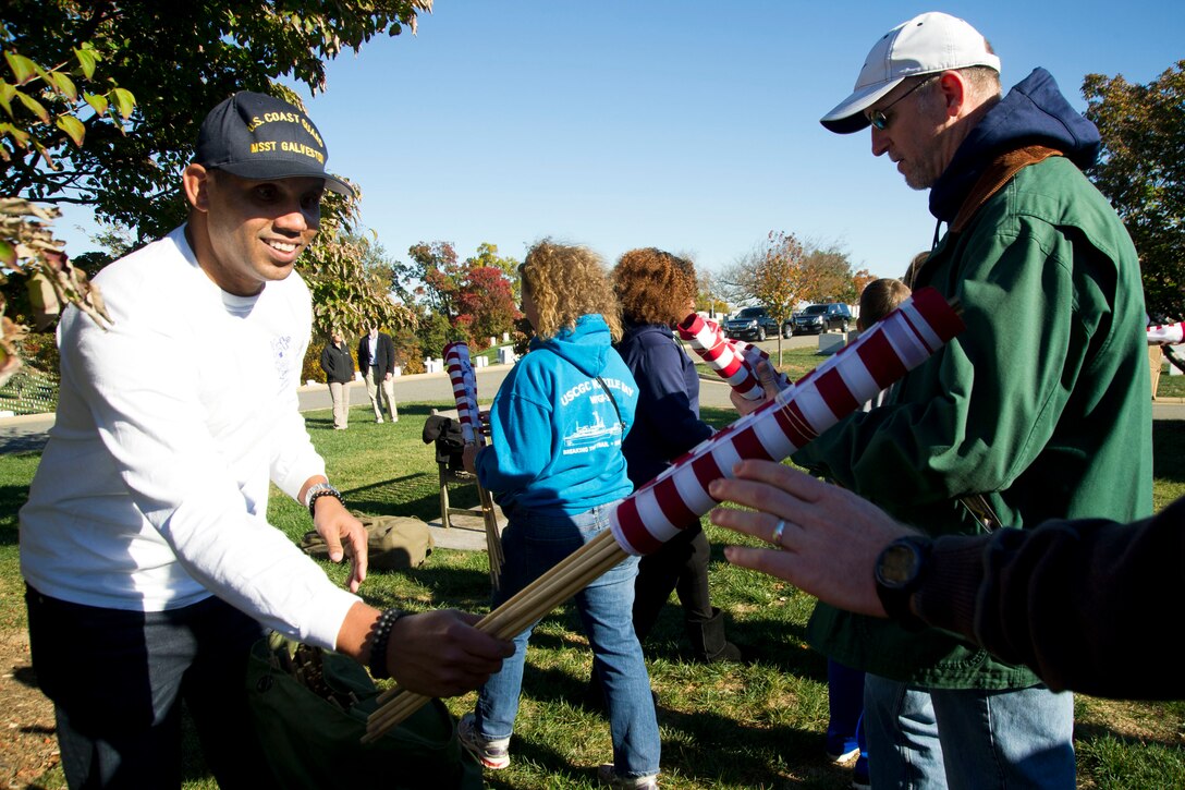 Coast Guard Chief Petty Officer Darien Moya hands out flags during the annual Flags Across America event at Arlington National Cemetery, Arlington, Va., Nov. 5, 2016. Coast Guard photo by Petty Officer 2nd Class Lisa Ferdinando