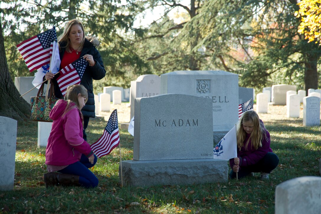 A Coast Guard family places flags at graves during the Flags Across America event at Arlington National Cemetery, Arlington, Va., Nov. 5, 2016. Coast Guard photo by Petty Officer 2nd Class Lisa Ferdinando