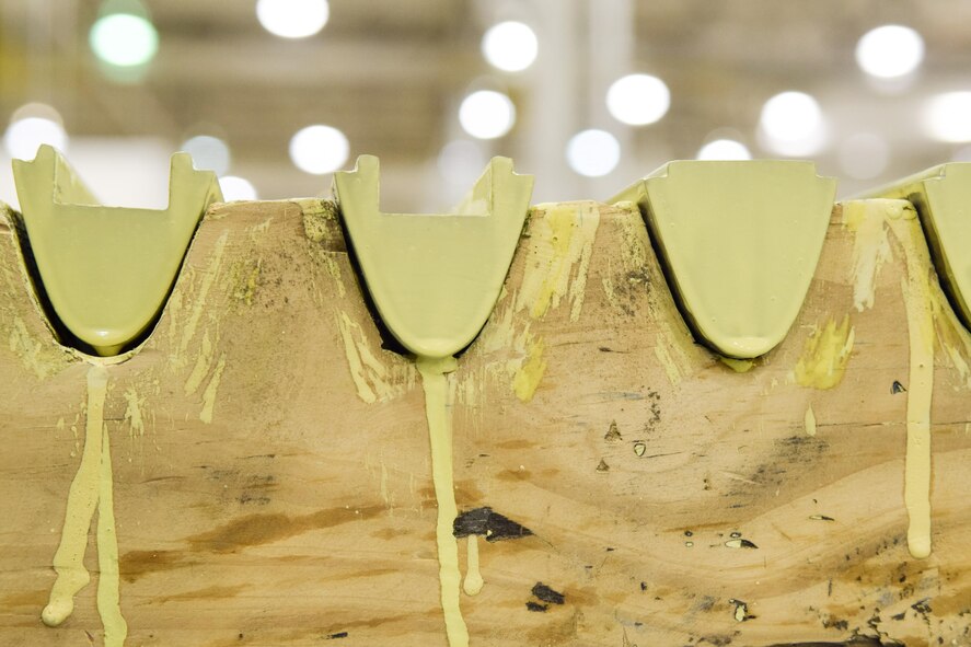 Newly painted KC-135 Stratotanker ruddervator weights sit in a cradle to dry as they are prepared for use by the 553rd Commodities Maintenance Squadron at the Oklahoma City Air Logistics Complex, July 25, 2016, Tinker Air Force Base, Okla. The yellow zinc-chromate is used to prevent corrosion on metal surfaces. (U.S. Air Force photo/Greg L. Davis)