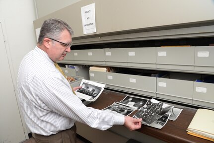 Lane Bourgeois, 12th Flying Training Wing historian looks at photographs Oct. 26, 2016 in his office on Joint Base San Antonio-Randolph. Bourgeois, who has also served as historian for the 71st FTW at Vance Air Force Base, Okla., Air Force Recruiting Service and the 31st Fighter Wing at Aviano Air Base, Italy, said he enjoys writing unit histories.