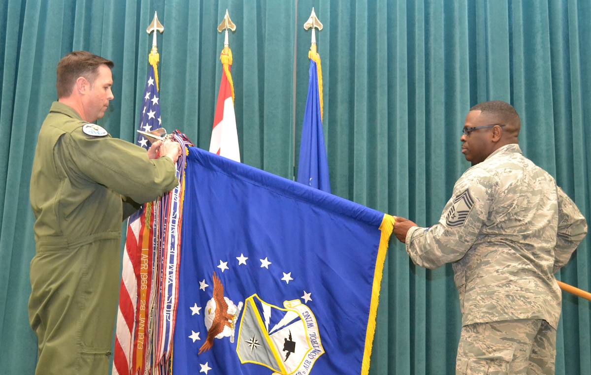 Chief Master Sgt. Michael Stephens, 552nd Air Control Wing’s chief enlisted manager, holds the wing guidon as Colonel Bradley Bird, 552nd ACW vice commander, attaches the Meritorious Unit Award streamer.  (Air Force photo by Ron Mullan)