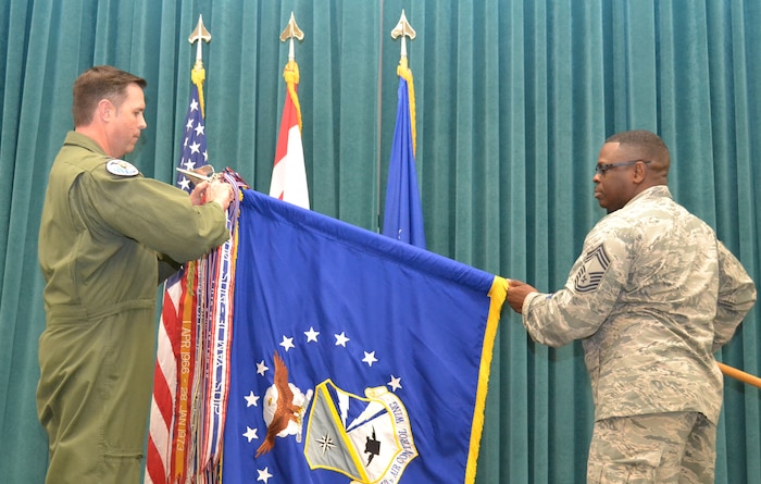 Chief Master Sgt. Michael Stephens, 552nd Air Control Wing’s chief enlisted manager, holds the wing guidon as Colonel Bradley Bird, 552nd ACW vice commander, attaches the Meritorious Unit Award streamer.  (Air Force photo by Ron Mullan)