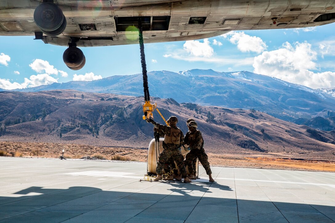 U.S. Marines with Combat Logistics Battalion 15, 1st Marine Logistics Group, and 3rd Battalion, 4th Marine Regiment, 1st Marine Division, grab a hook lowered by a CH-53E Super Stallion, with Marine Heavy Helicopter Squadron 466, to pick up a 500-gallon drum of water during a Helicopter Support Team drill at Mountain Warfare Training Center, Bridgeport, Calif., Oct. 25, 2016. The Marines use a pole to grab the hook lowered by the helicopter to ground the electrical currents before grabbing it by hand. The drum was taken into the Sierra Mesa Mountains to support Marines who are conducting field operations during Mountain Exercise 6-16. (U.S. Marine Corps photo by Lance Cpl. Adam Dublinske)