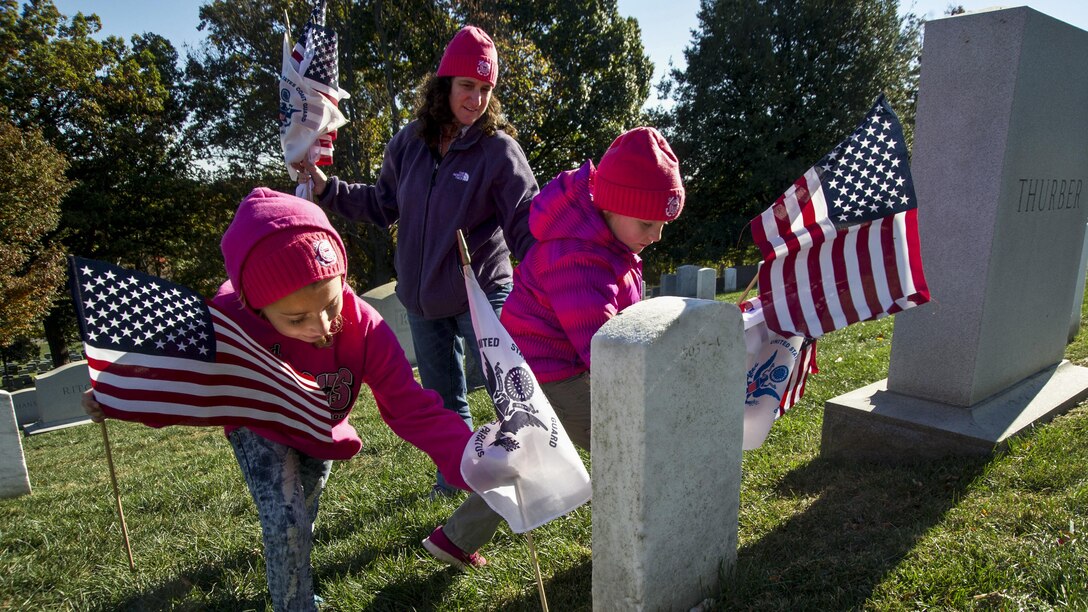 Coast Guard Lt. Cmdr. Melissa Ransom and her daughters partitipate in the annual Flags Across America event at Arlington National Cemetery in Arlington, Va., Nov. 5, 2016. Coast Guard members, their friends and families placed American and Coast Guard flags on the graves of Coast Guardsmen at the cemetery. The Coast Guard Chief Petty Officers Association's Washington, D.C., chapter holds the annual event the weekend before Veterans Day. Coast Guard photo by Petty Officer 2nd Class Lisa Ferdinando