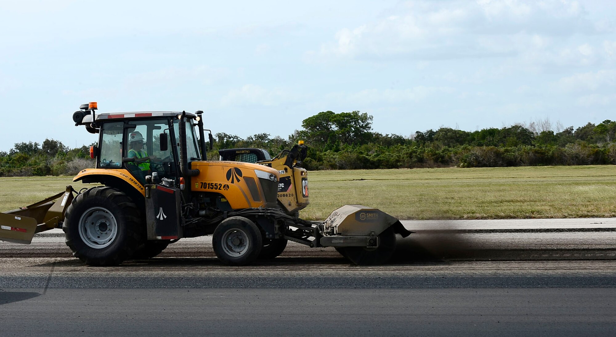 A tractor with a broom attachment sweeps asphalt debris into a pile along the runway at MacDill Air Force Base Fla., Oct. 27, 2016. Construction on MacDill’s runway started Oct. 20, 2016 and is scheduled to be finished in 60 days. (U.S. Air Force photo by Senior Airman Tori Schultz)