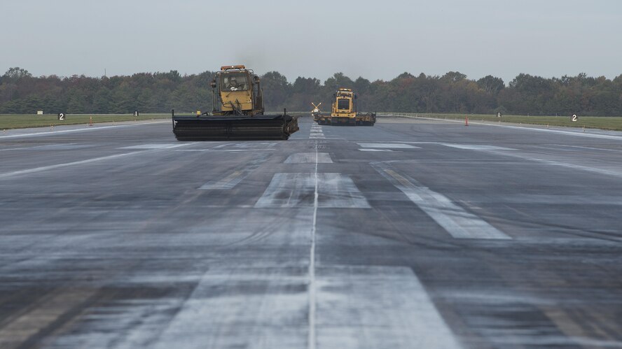 Two Oshkosh Snow Brooms conduct rubber removal operations on Runway 14-32 Nov. 1, 2016, at Dover Air Force Base, Del. Built up rubber residue is not only unsafe for aircraft, it also may cover up important paint markings on the airfield. (U.S. Air Force photo by Senior Airman Zachary Cacicia)