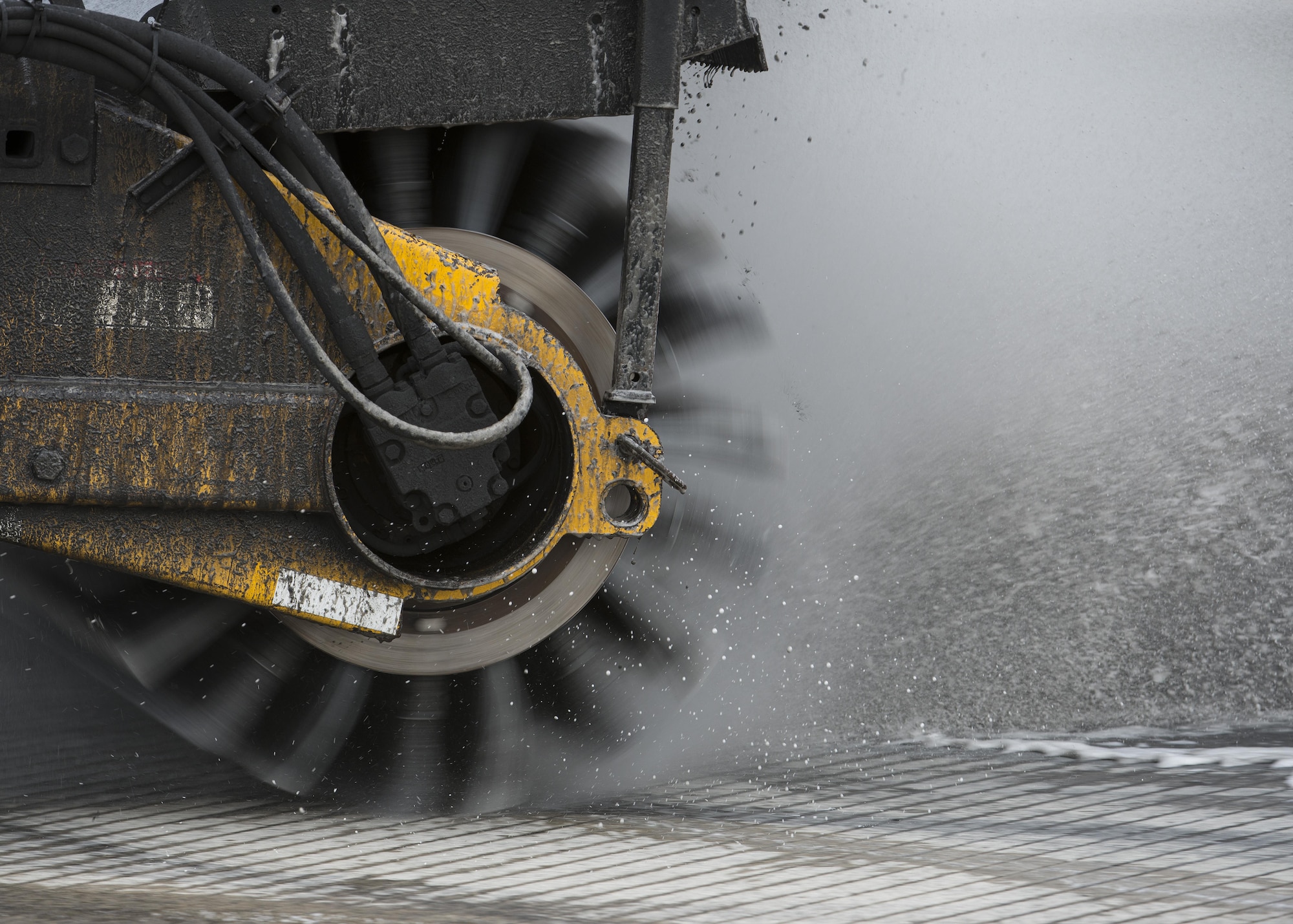 An Oshkosh Snow Broom brushes rubber residue off of Runway 14-32 during rubber removal operations Nov. 1, 2016, at Dover Air Force Base, Del. Rubber residue is left on the runway every time an aircraft makes a landing and builds up over time making runway markings harder to see. (U.S. Air Force photo by Senior Airman Zachary Cacicia)
