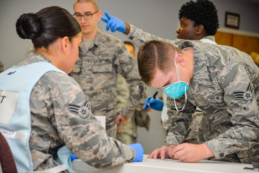 U.S. Air Force Senior Airman Zackery Chenevey, an exercise participant, fills out a health questionnaire with the assistance of Senior Airman Loran Lozano, 88th Medical Group patient administration, during a base exercise, Nov. 3, 2016 at Wright-Patterson Air Force Base, Ohio. Members of the 88th Air Base Wing Medical Group participated in an exercise this last week to test their level of readiness to respond to a simulated outbreak of Swine Flu. (U.S. Air Force photo / Staff Sgt. Ashley Clingerman)