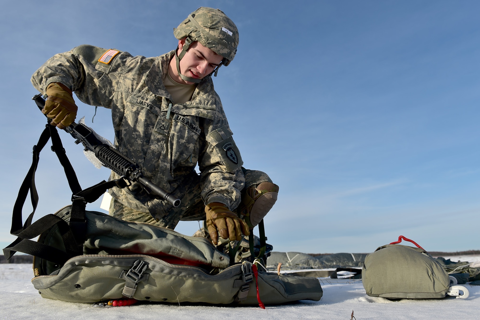 U.S. Army Pfc. Jonathan Jarvis, a native of Muldrow, Okla., assigned to Headquarters and Headquarters Battery, 2nd Battalion, 377th Parachute Field Artillery Regiment, 4th Infantry Brigade Combat Team (Airborne), 25th Infantry Division, U.S. Army Alaska, removes his weapon from its case after an airborne training jump from a CH-47 Chinook helicopter on Malemute drop zone at Joint Base Elmendorf-Richardson, Alaska, Thursday, Nov. 3, 2016. The Soldiers of 4/25 IBCT belong to the only American airborne brigade in the Pacific and are trained to execute airborne maneuvers in extreme cold weather/high altitude environments in support of combat, partnership and disaster relief operations. 