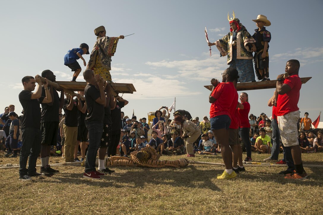 Scouts from Scout Association of Japan stand on platforms carried by Marine volunteers during the 23rd Boy Scouts of America-Scout Association of Japan Friendship Jamborette Nov. 5-6 aboard Camp Kinser, Okinawa, Japan. Scouts from both the SAJ and Boy Scouts of America experienced many Okinawan traditions such as tug-of-war, karate exhibitions, a sanshin performance and shishimai dance performance. The tug-of-war is can be traced back in Okinawan history as far back as the seventeenth century. (U.S. Marine Corps photo by Cpl. Daniel Jean-Paul / Released)