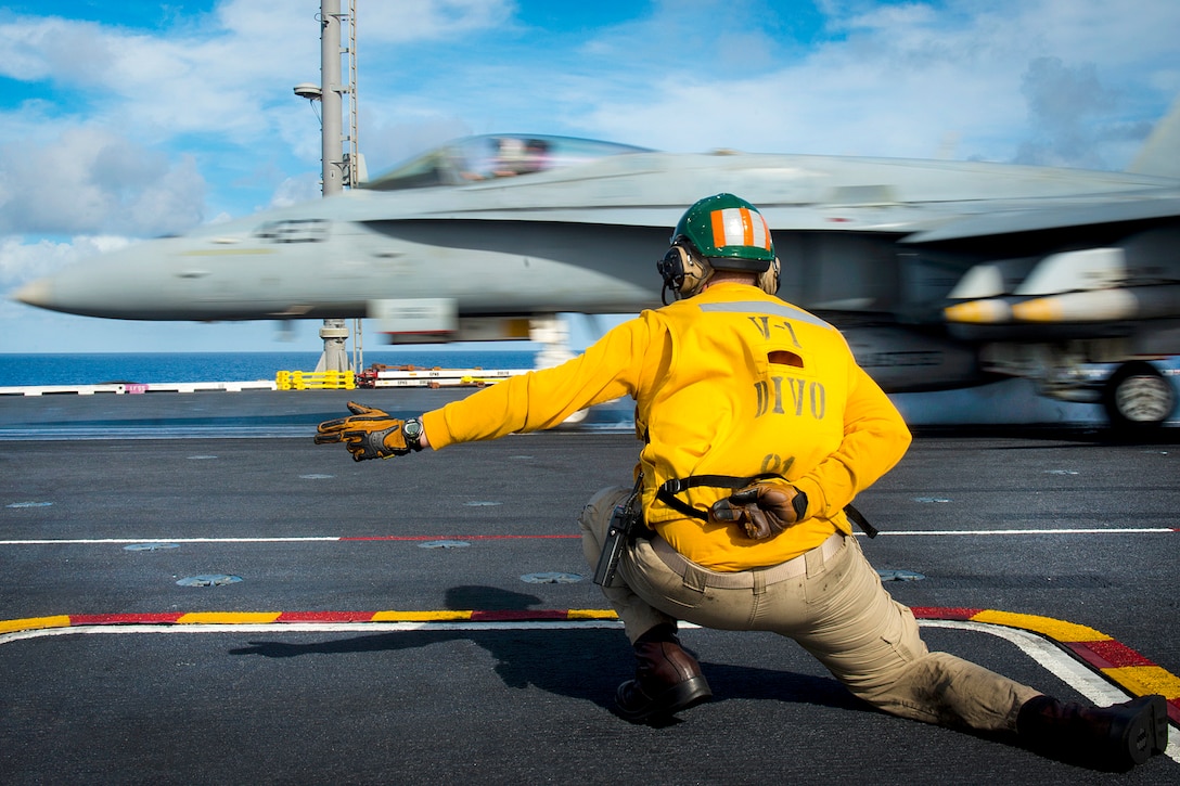 Navy Lieutenant Daniel Didier directs an F/A-18C Hornet during flight operations on the aircraft carrier USS Carl Vinson in the Pacific Ocean, Oct. 31, 2016.  Navy photo by Petty Officer 3rd Class Matthew Brown
