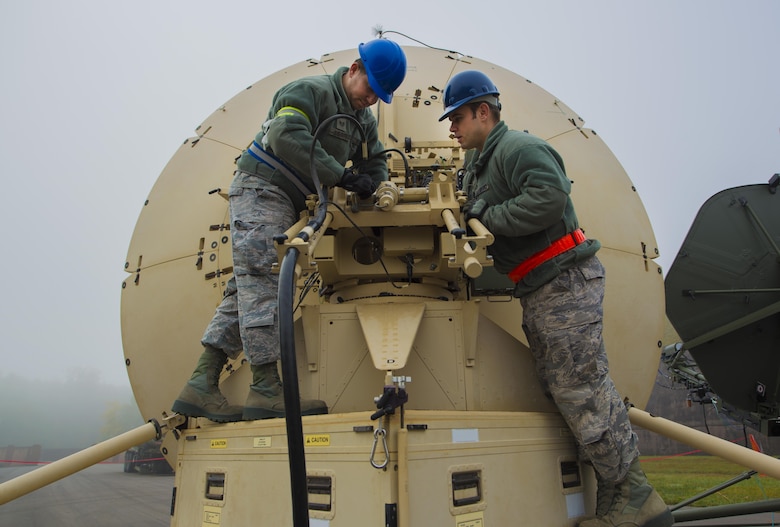 Staff Sgt. Al Lotito, 1st Combat Communications Squadron radio frequency transmission systems technician, and Tech. Sgt. Richard Rawls, 1st CBCS cyber system operator, attach a power cable to a satellite during the exercise Healthy Thunder at Ramstein Air Base, Germany, Oct. 27, 2016. The 1st CBCS Airmen set up all communications as if in a deployed location, and defended their site from opposing forces. (U.S. Air Force photo by Senior Airman Tryphena Mayhugh)