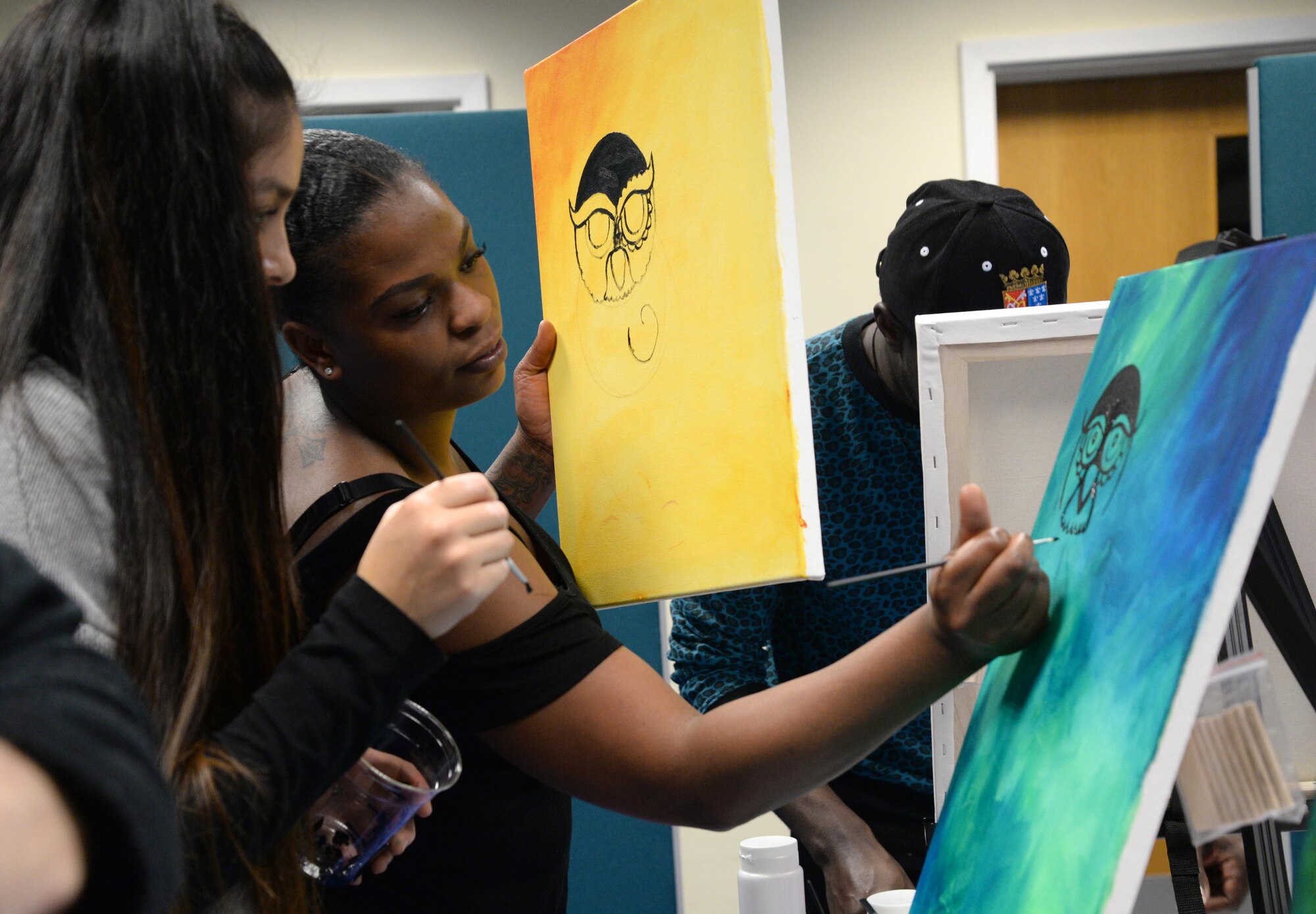 U.S. Air Force Tech. Sgt. Ceji Dorty, 488th Intelligence Squadron logistic support, center, demonstrates painting techniques to a student, Nov. 4, 2016, at the ‘Breathe, Sip, Paint’ event on RAF Mildenhall. As the class painted, a nutritionist talked about the health benefits of certain fruits and vegetable. (U.S. Air Force photo by Senior Airman Justine Rho) 