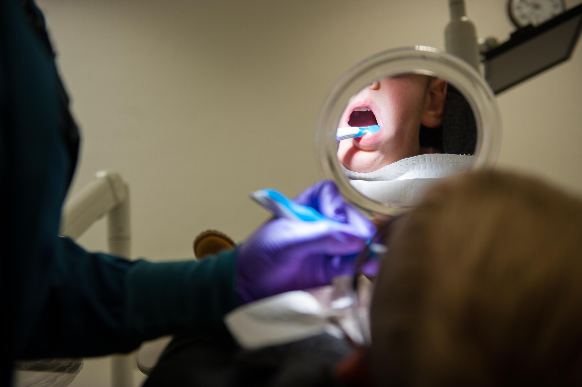 Channing Wray, holds a mirror to watch as his dentist cleans his teeth during the “Little Teeth, Big Smile” event at Ramstein Air Base, Germany, Nov. 5, 2016. The event was a way for children up to 10 years old to get their teeth checked or cleaned in an environment tailored to their age group. According to the Center for Disease and Control, tooth decay is one of the most common chronic conditions of childhood in the United States. Untreated cavities can cause pain and infections that may lead to problems with eating, speaking, playing, and learning. (U.S. Air Force photo by Airman 1st Class Lane T. Plummer)
