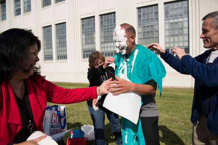 The 2016 Combined Federal Campaign (CFC) co-coordinators for Naval Surface Warfare Center, Carderock Division, Anna Eshbaugh (left) and Despi Mahaney, lend a
hand to Tariq Al-Agba, head of the Contracts Department (Code 02), after he took a pie in the face to raise money for CFC at the Carderock CFC kick-off tailgate event Oct. 26, 2016, in West Bethesda, Md. (U.S. Navy photo by Monica McCoy/Released)