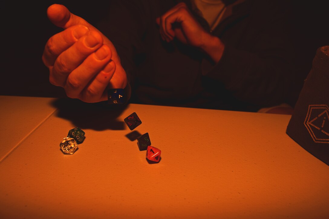 Airman 1st Class Cody Kirby, a pavement and equipment operations apprentice assigned to the 28th Civil Engineer Squadron, rolls the dice for his character in a role playing game at Ellsworth Air Force Base, S.D., Nov. 1, 2016. During a recent deployment, Kirby discovered board games as a way to occupy several people when weather conditions encourage indoor activity. (U.S. Air Force photo by Airman 1st Class James L. Miller)