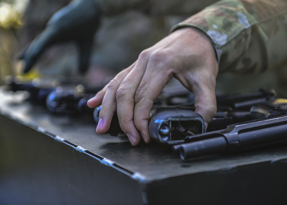 U.S. Air Force Airmen, U.S. Army Soldiers and U.S. Navy Sailors select a 9 mm Beretta automatic pistol during the German Armed Forces Badge for military Proficiency event at Joint Base Langley-Eustis, Va., Nov. 4, 2016.   The pistol exercise is one of six GAFBP events, members fire two bullets in three different positions, aiming to hit the target each time. (U.S. Air Force photo/Tech Sgt. Daylena S. Ricks)