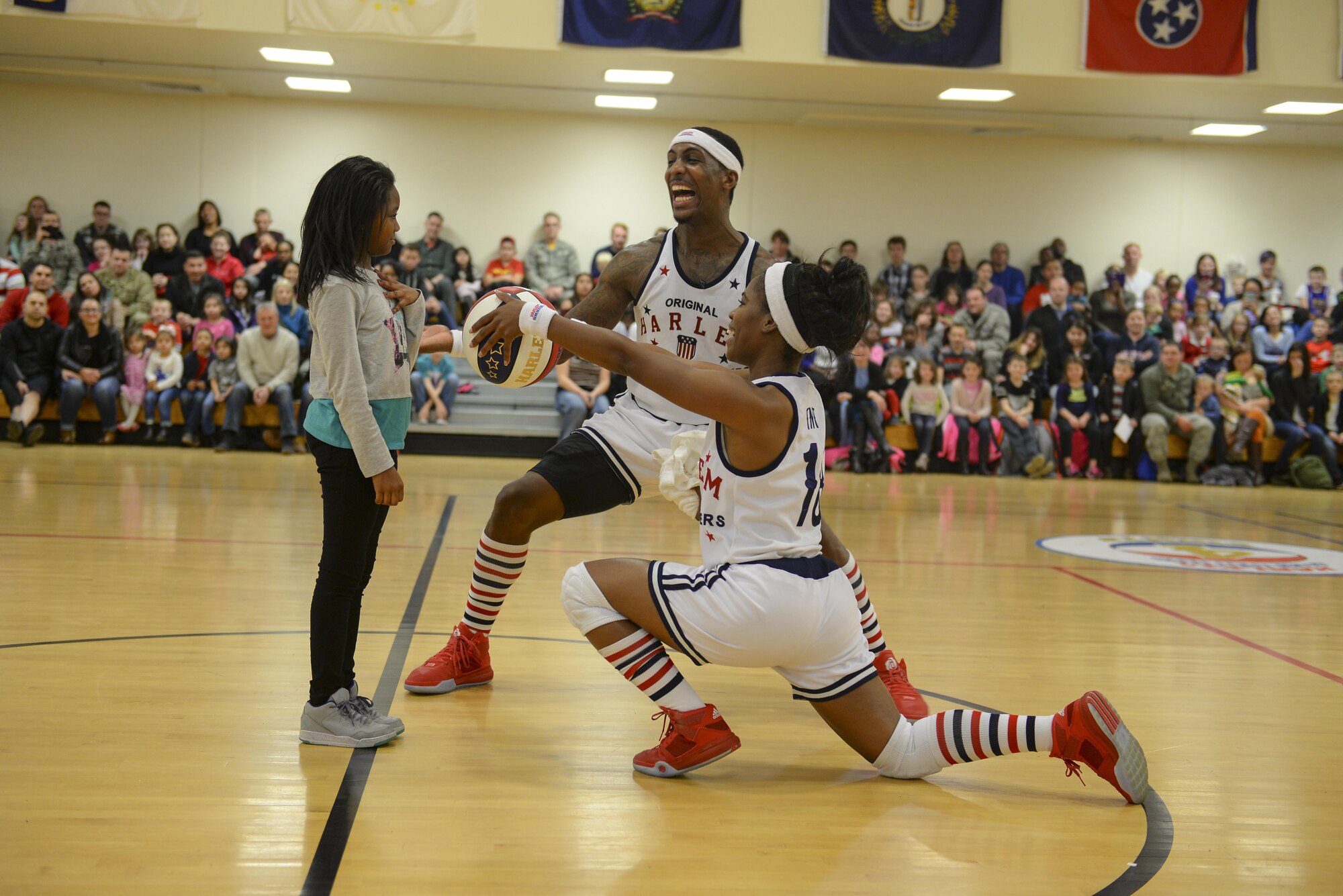 Harlem Globetrotters guard, TNT, right, and forward, Bull, present a basketball to an audience member Nov. 4, 2016, at the Hardstand Fitness Center on RAF Mildenhall, England. Throughout the performance audience members were selected to participate in the show. (U.S. Air Force photo by Staff Sgt. Micaiah Anthony)