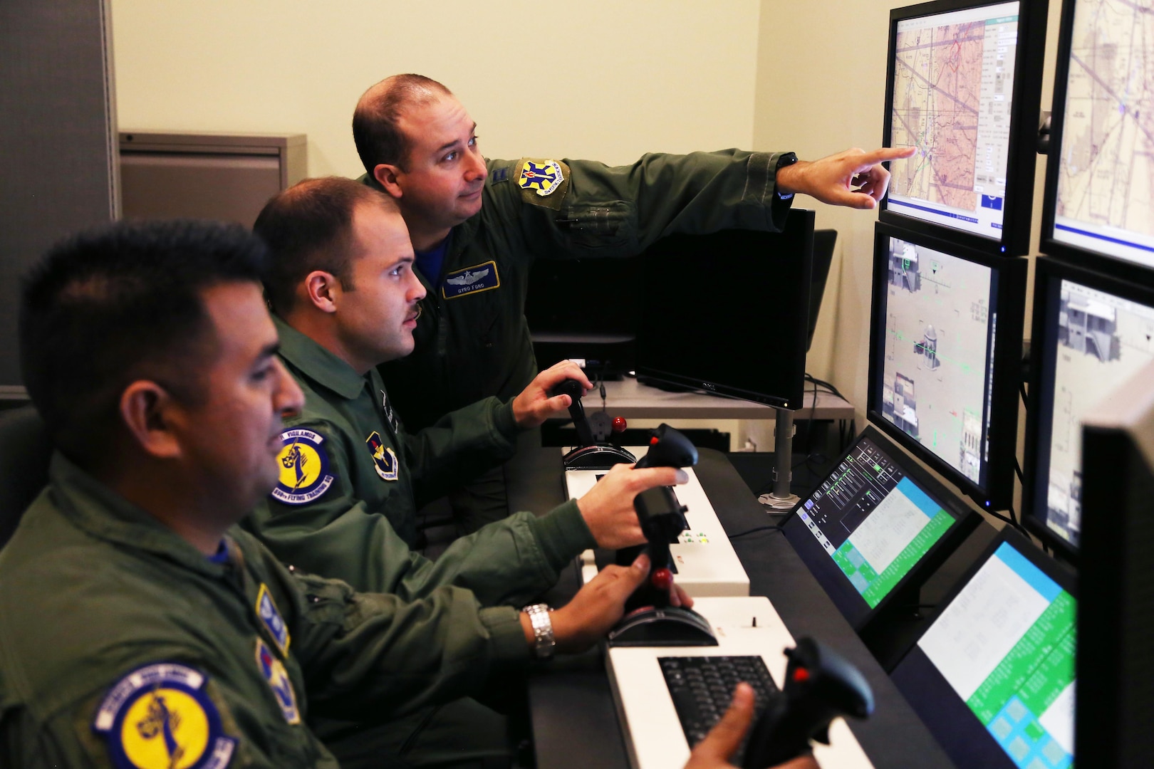 Front to back: Staff Sgt. Jesus, 558th Flying Training Squadron sensor operator instructor, and 2nd Lt. James, 558th FTS Remotely Piloted Aircraft pilot trainee, are instructed by Capt. Gary, 558th FTS instructor pilot on weapons employment procedures. 
