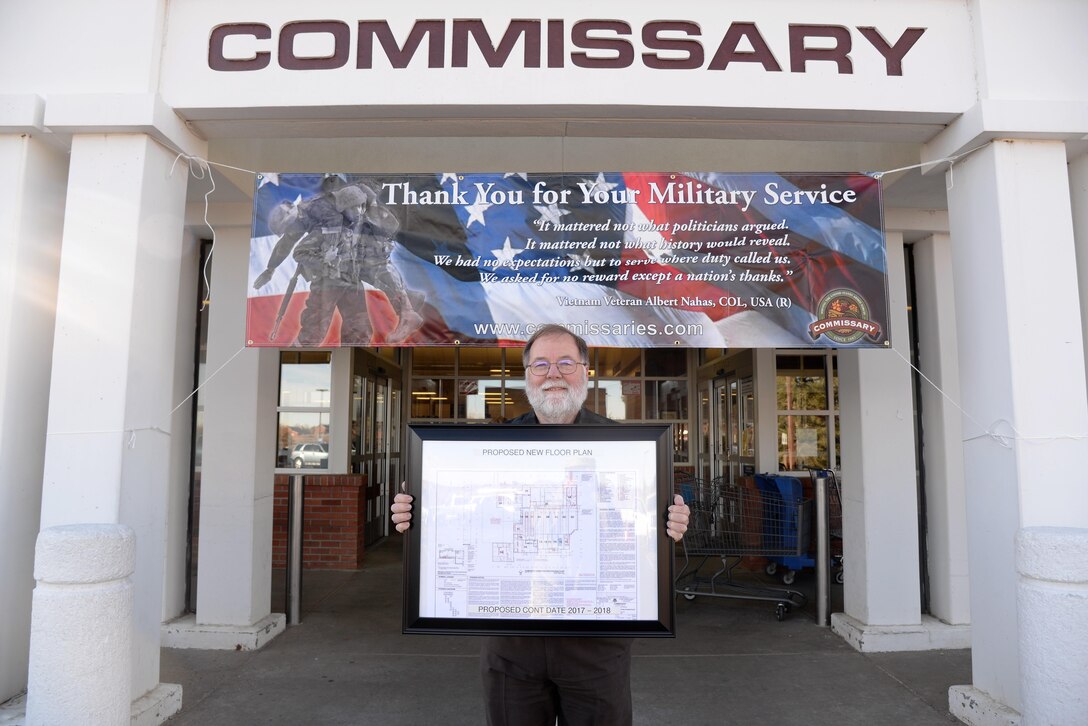 Mr. James Freeman, commissary store director, stands in front of the commissary entrance displaying renovation floor plans at F.E. Warren Air Force base, Wyo., Nov. 8, 2016.  The commissary renovations will provide an enhanced shopping experience to customers and is scheduled to be completed in late 2018.