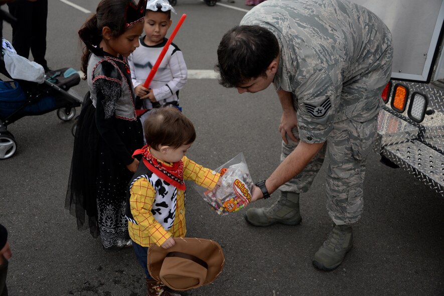 A child wearing a Woody, the Sheriff costume, grabs some candy during the 5th Annual Trunk-or-Treat event at Travis Air Force Base, Calif., Oct. 28, 2016. More than 2,000 people attended the event which provided a safe place for military families to enjoy Halloween festivities. (U.S. Air Force photo/Tech. Sgt. James Hodgman) 