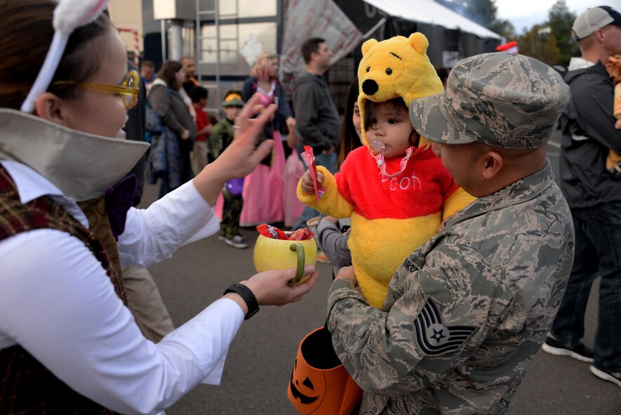 Tech. Sgt. Ronulfo Dipasupil, 60th Civil Engineer Squadron, holds his daughter while she receives candy during the 5th Annual Trunk-or-Treat event at Travis Air Force Base, Calif., Oct. 28, 2016. More than 2,000 people attended the event which provided a safe place for military families to enjoy Halloween festivities. (U.S. Air Force photo/Tech. Sgt. James Hodgman) 