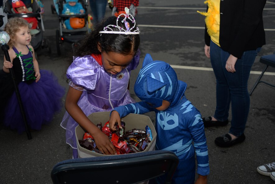 Two children grab some chocolate candy during the 5th Annual Trunk-or-Treat event at Travis Air Force Base, Calif., Oct. 28, 2016. More than 2,000 people attended the event which provided a safe place for military families to enjoy Halloween festivities. (U.S. Air Force photo/Tech. Sgt. James Hodgman)