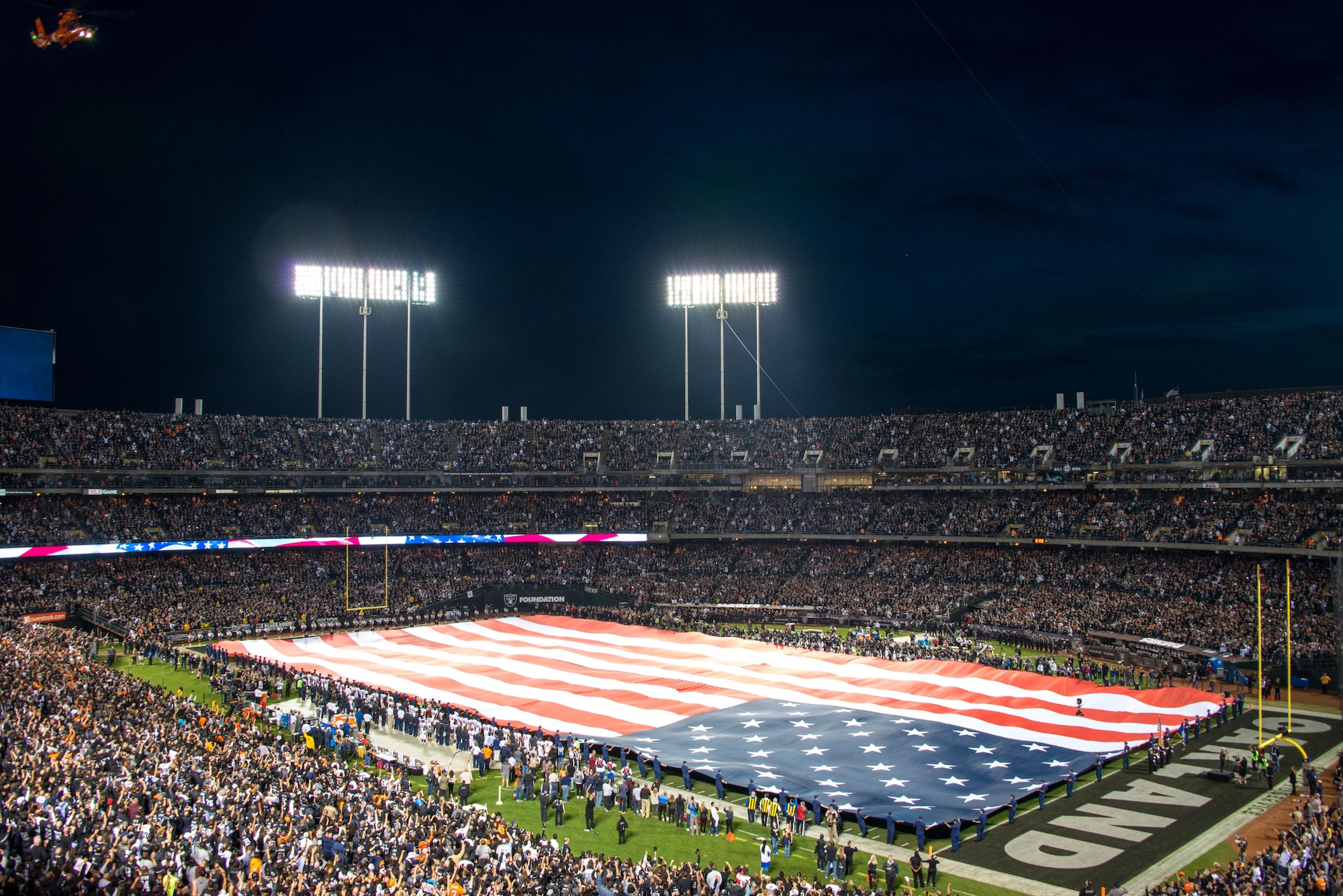 An HH-65 Dolphin U.S. Coast Guard helicopter does a fly-by during the playing of the National Anthem at the Oakland Coliseum prior to the Oakland Raiders Salute to Service game against the Denver Broncos Nov 6, 2016. The National Football League honors members of the U.S. military with its "Salute to Service" campaign during the month of November. (U.S. Air Force photo/Louis Briscese)