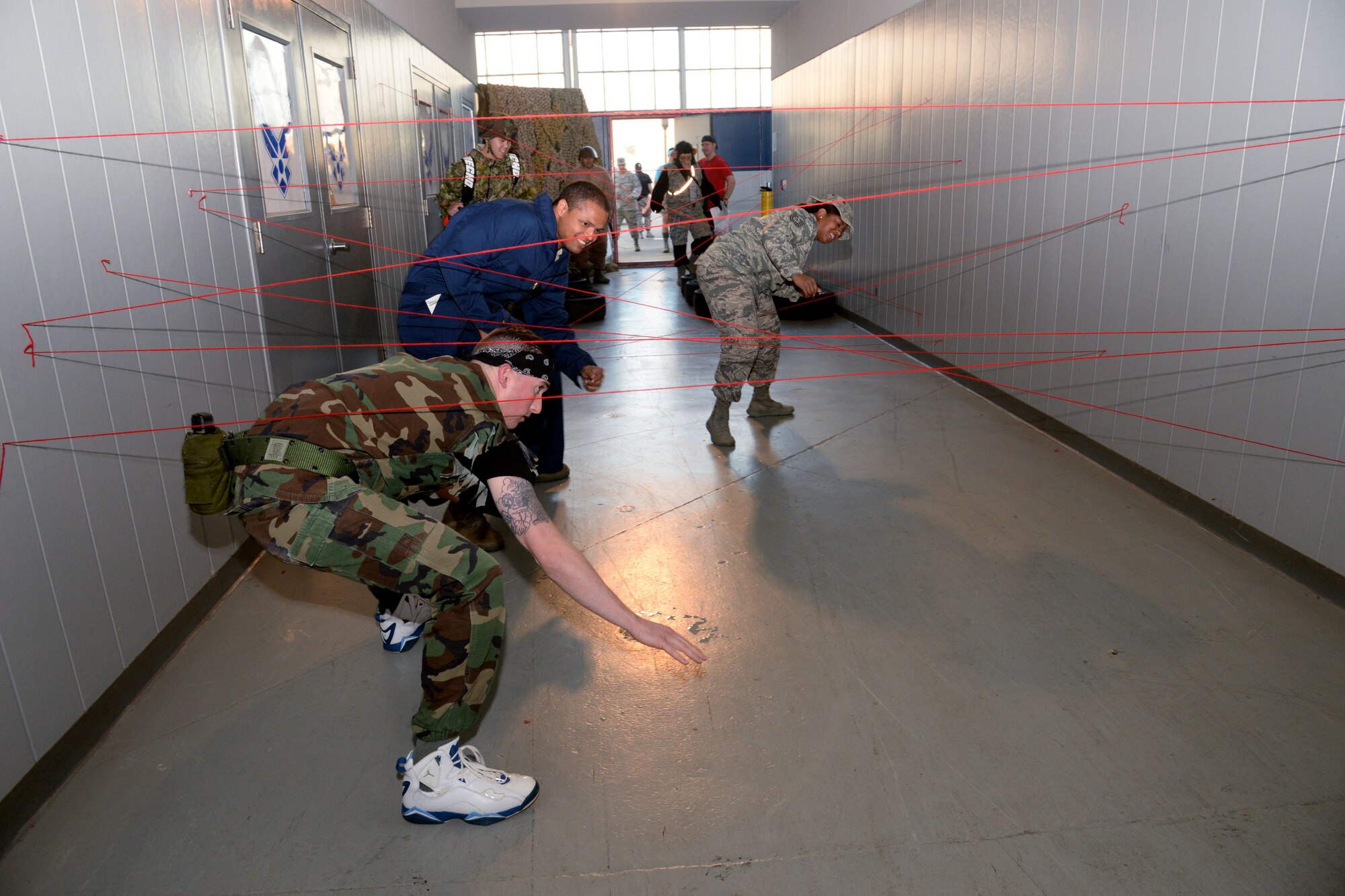 Maxwell Combat Dining-In attendees move through an obstacle course to enter the event, Nov. 4, 2016, Maxwell Air Force Base, Ala. Airmen has to jump through tires and maneuver through red yarn meant to mimic laser beams to be allowed entrance into the event. (U.S. Air Force photo/ Senior Airman Alexa Culbert)
