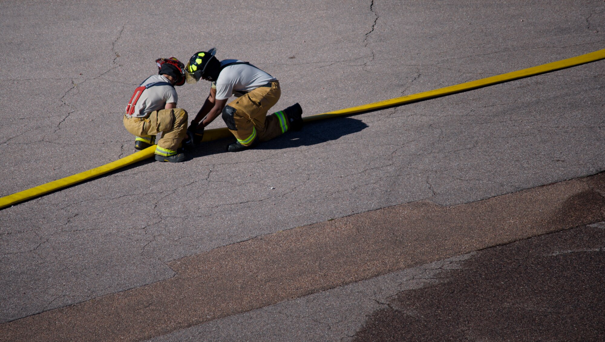 PETERSON AIR FORCE BASE, Colo. – Firemen assigned to the Peterson Air Force Base Fire Department disconnect a hose after a simulated structure fire during Condor Crest at Peterson AFB, Colo., Nov. 3, 2016.  Condor Crest is a wing-wide exercise used to evaluate crisis response and unit effectiveness. (U.S. Air Force photo by Airman 1st Class Dennis Hoffman)