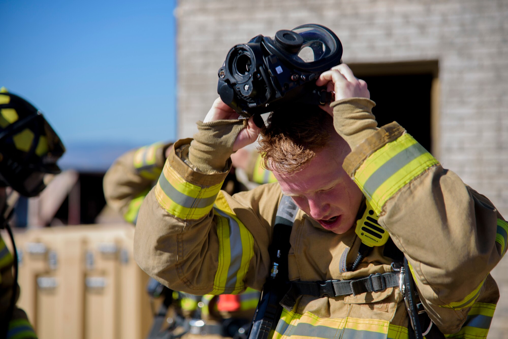 PETERSON AIR FORCE BASE, Colo. – Airman 1st Class Daniel Ray, Peterson Air Force Base Fire Department fireman, removes his gas mask after responding to a simulated structure fire in during Condor Crest at Peterson AFB, Colo., Nov. 3, 2016.  Condor Crest is a wing-wide exercise used to evaluate crisis response at Peterson AFB. (U.S. Air Force photo by Airman 1st Class Dennis Hoffman)