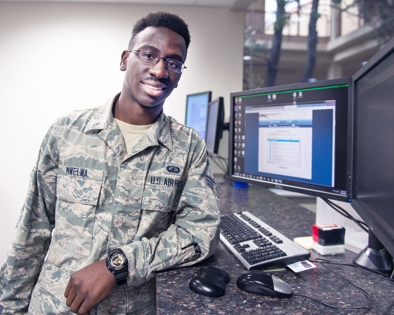 U.S. Air Force Senior Airman Michael Mwelwa, 60th Comptroller Squadron, poses for a photo by his workstation at Travis Air Force Base, Calif., Oct. 25, 2016. Mwelwa was recently awarded U.S. citizenship after coming to the United States at the age five from The Republic of Zambia. (U.S. Air Force photo/Louis Briscese)