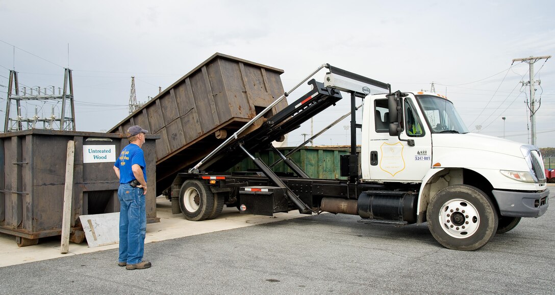 Deral Freysinger, 436th Civil Engineer Squadron qualified recycling program manager, watches Dan Johnson of DataGuard Recycling, Greenwood, Del., pick up a roll-off container full of plastic Nov. 3, 2016, at the Recycling Center on Dover Air Force Base, Del. Freysinger stated that Dover AFB diverts 60 percent of its trash towards recycling which exceeds the Department of Defense goal of 55 percent. (U.S. Air Force photo by Roland Balik)