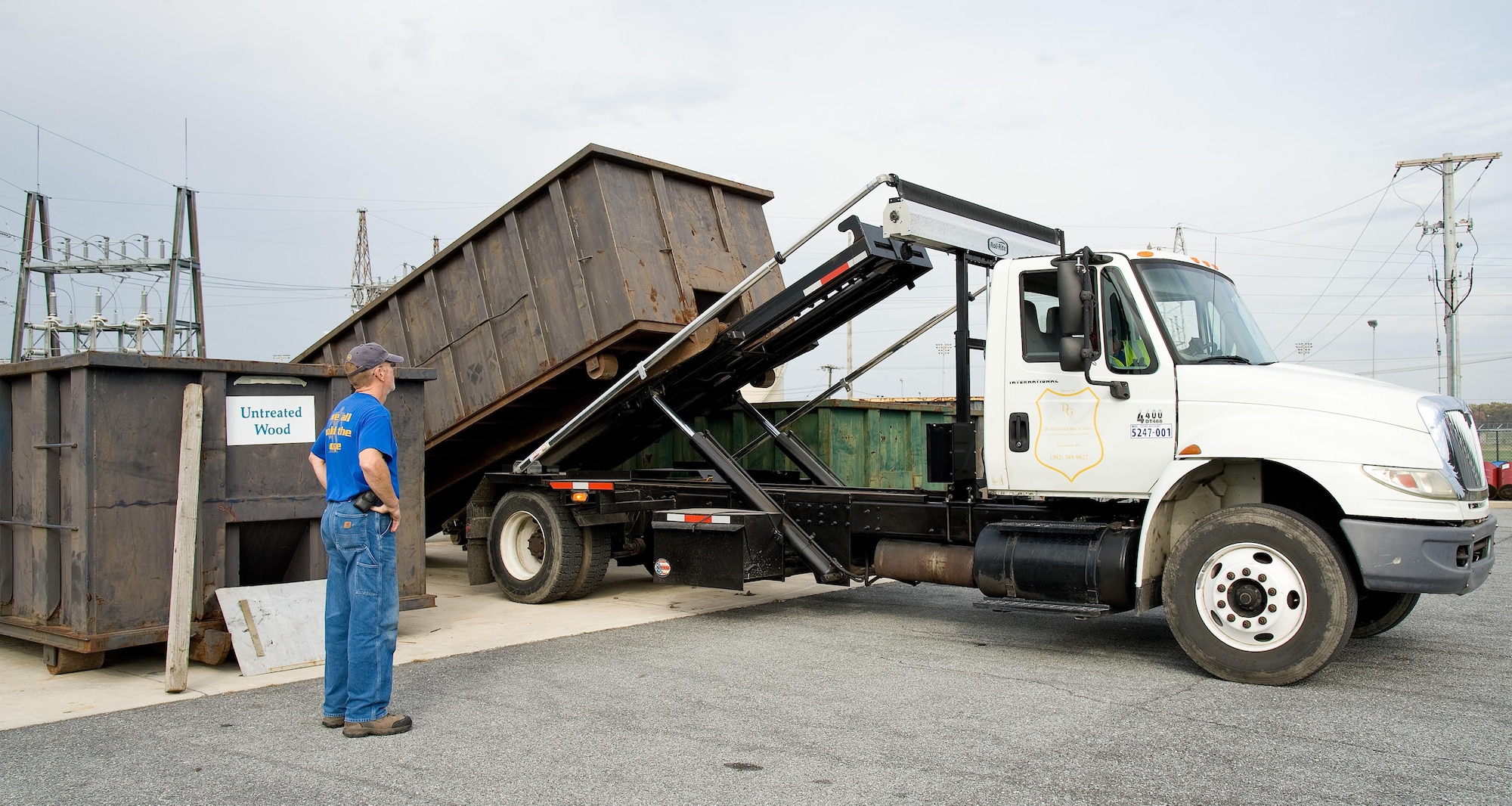Deral Freysinger, 436th Civil Engineer Squadron qualified recycling program manager, watches Dan Johnson of DataGuard Recycling, Greenwood, Del., pick up a roll-off container full of plastic Nov. 3, 2016, at the Recycling Center on Dover Air Force Base, Del. Freysinger stated that Dover AFB diverts 60 percent of its trash towards recycling which exceeds the Department of Defense goal of 55 percent. (U.S. Air Force photo by Roland Balik)