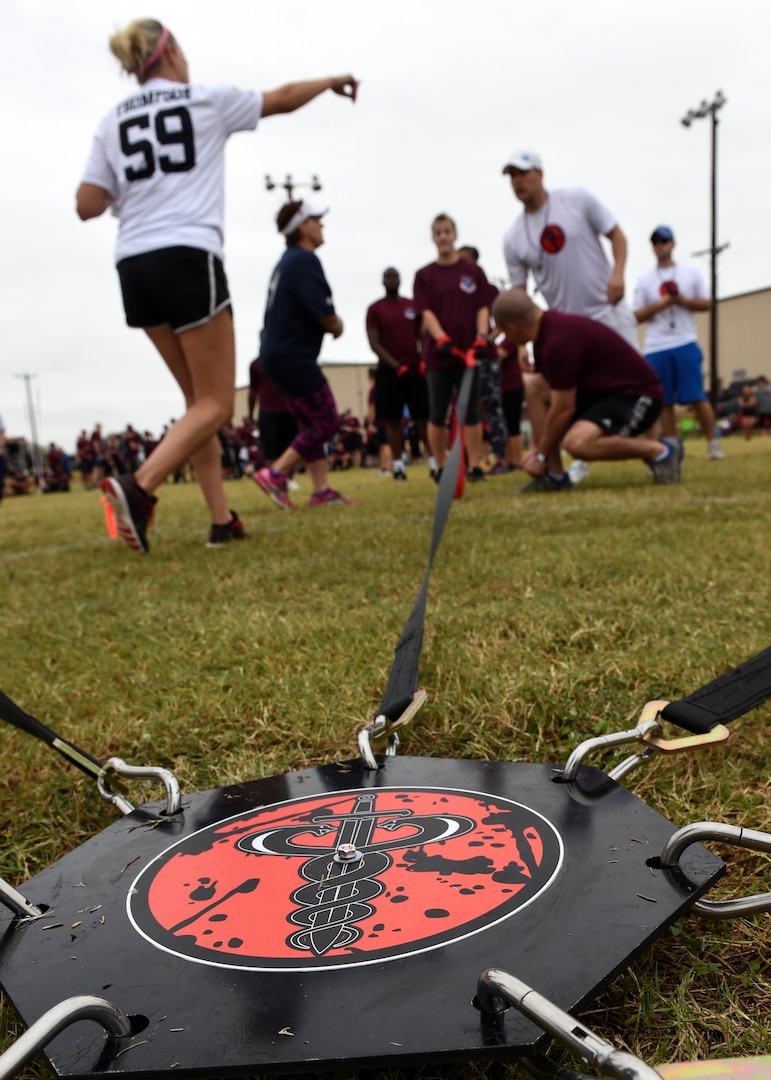 Airmen from the 59th Medical Wing’s seven groups get ready for the seven-way tug-of-war Nov. 4 during the Warrior Medic Challenge on Joint Base San Antonio-Lackland, Texas. Seven ropes were connected to a metal disc that was centered in the middle of a heptagonally-marked field. The 59th Medical Operations Group pulled the center ring across its border first to win the competition. (U.S. Air Force photo/Staff Sgt. Kevin Iinuma)