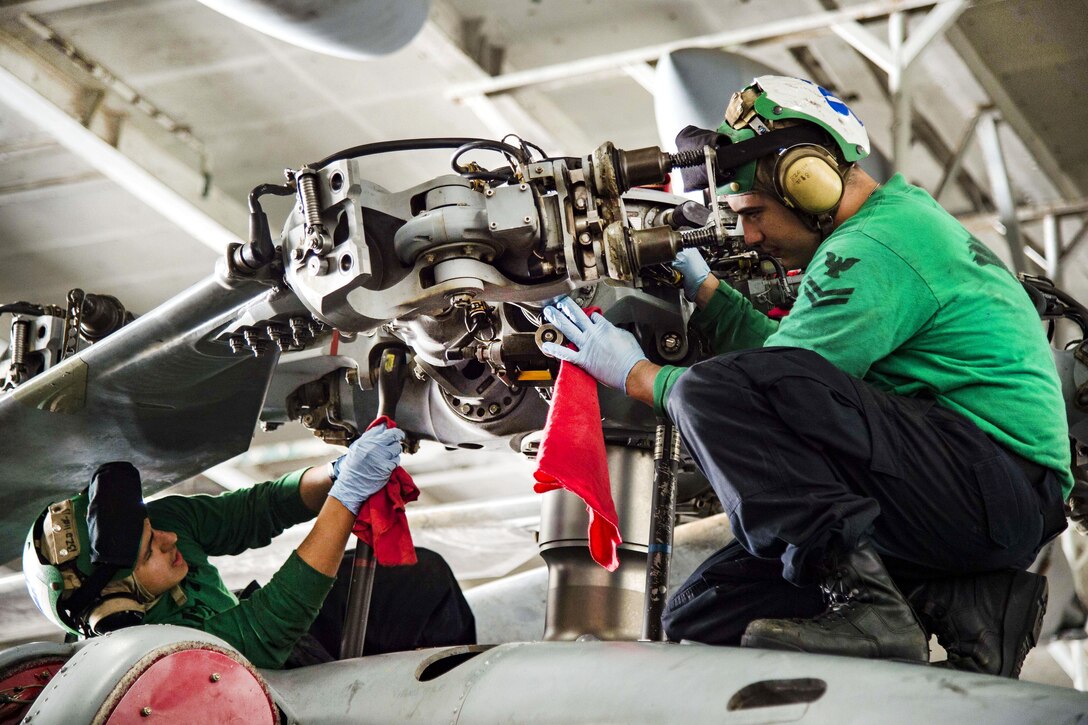 Navy Petty Officer 2nd Class Shawn Hobgood, right, and Seaman Alex Blanco perform a 14-day special inspection on an MH-60R Sea Hawk helicopter in the hangar bay of the aircraft carrier USS Dwight D. Eisenhower in the Persian Gulf, Nov. 7, 2016. The helicopter is assigned to Helicopter Maritime Strike Squadron 74. Navy photo by Petty Officer 3rd Class Nathan T. Beard