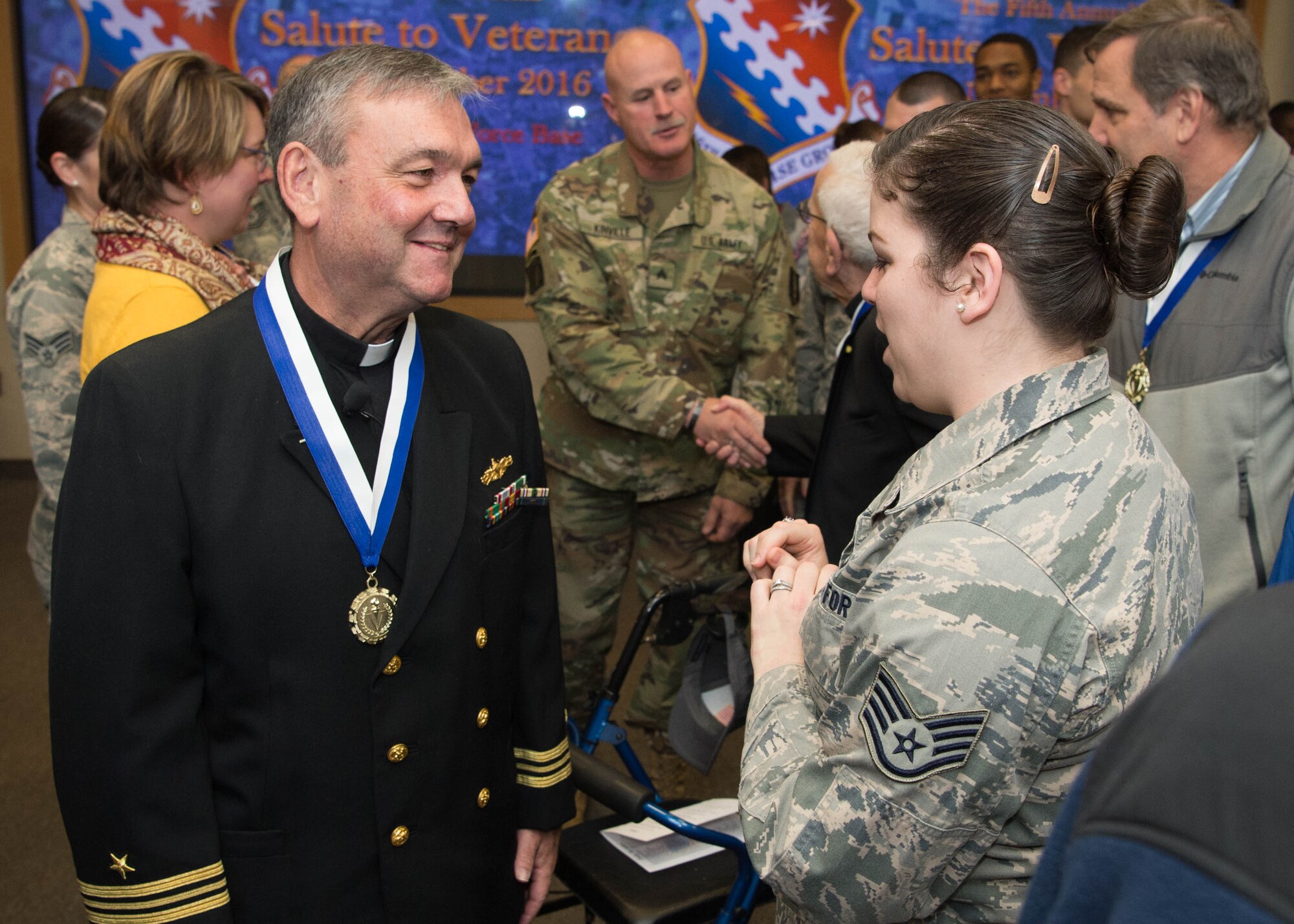 Retired U.S. Navy Lt. Cmdr. Richard Burton, now a Roman Catholic priest for the Archdiocese of Boston, meets Staff Sgt. Marjorie Brooks, 319th Recruiting Squadron personnelist, following the fifth annual Salute to Veterans at the Hanscom Conference Center Nov. 9. Burton was the event's guest speaker. The ceremony recognized local veterans for their service to the nation. (U.S. Air Force photo by Jerry Saslav)