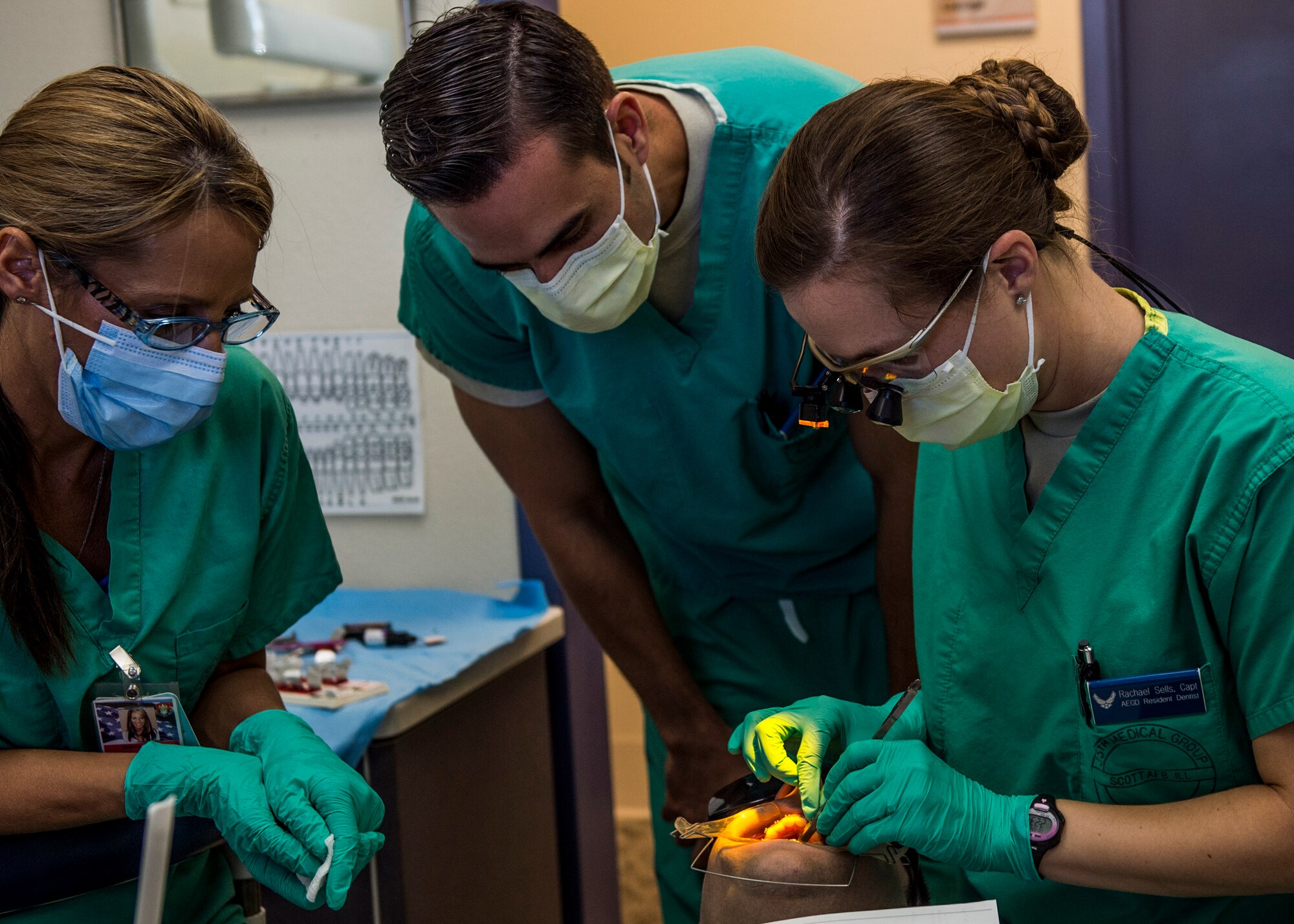 Maj. David Servello, chief of orthodontics, overseas the work of Capt. Rachael Sells as she conducts an operation giving a patient braces, Scott Air Force Base, Ill., Oct. 25, 2016. Sells is one of four residents in the Advanced Education in General Dentistry Program.