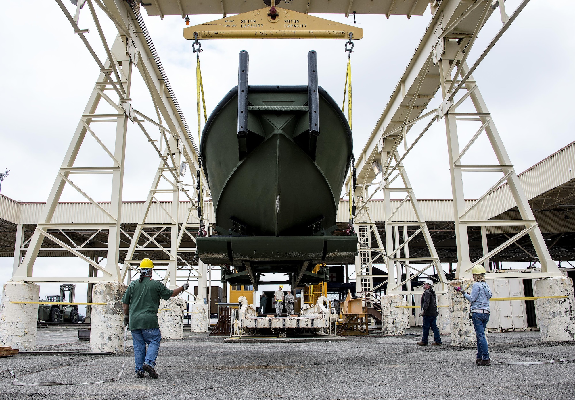 Aerial porters assigned to the 60th Aerial Port Squadron hoist a U.S. Army Bridge Erection Boat with a crane onto the unit's loading dock May 6, 2016, at Travis Air Force Base, Calif.The BEB assembles rafts and bridges by maneuvering one to four bay combinations of ramp and interior bays forward, reverse and sideways in water current speeds up to six feet per second. (U.S. Air Force photo by Staff Sgt. Charles Rivezzo)