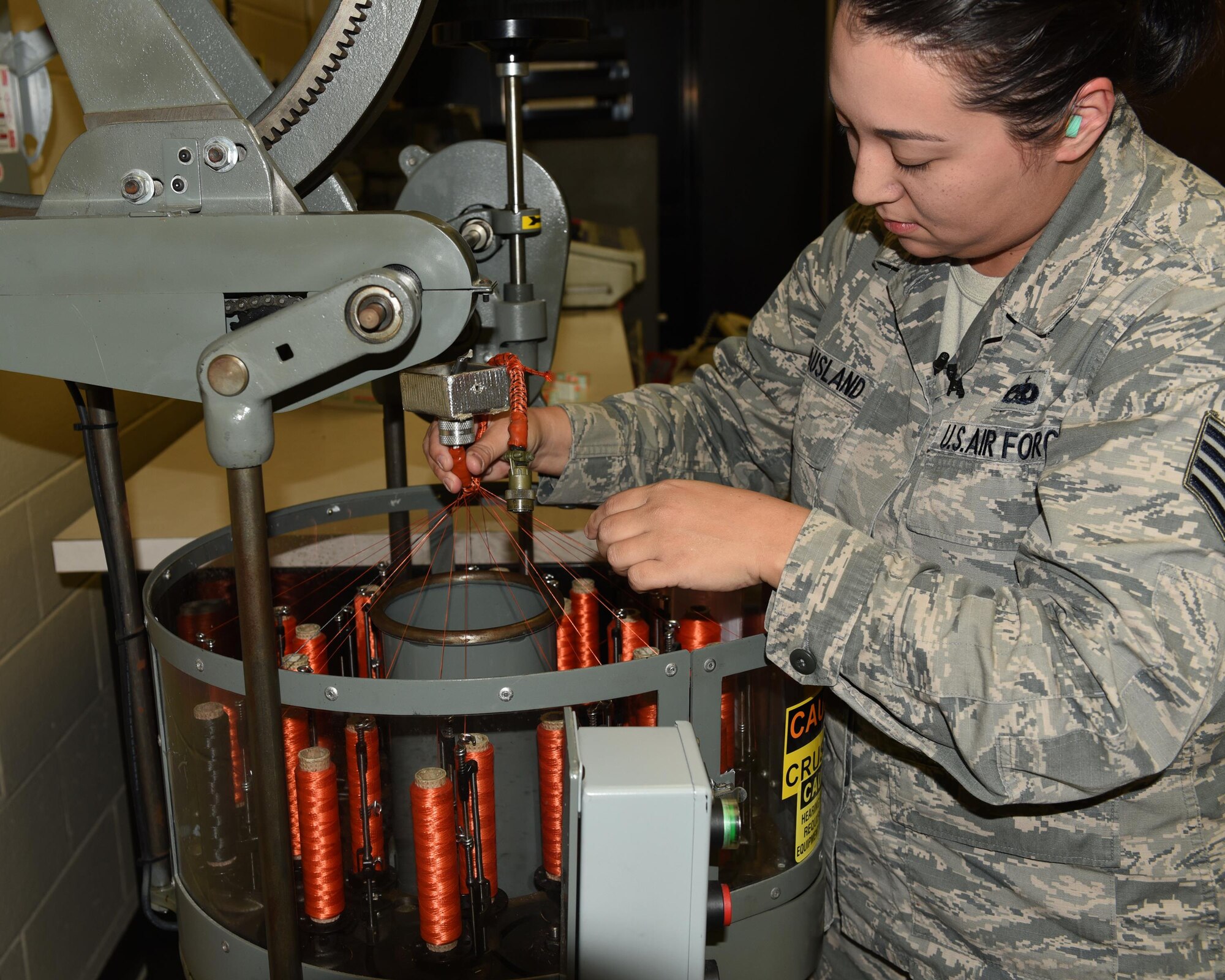 U.S. Air Force Staff Sgt. Elizabeth McCausland, 53rd Test Support Squadron Special Devices Flight electrical and environmental systems specialist, uses a wire harness machine to protect critical wiring on aircraft at Tyndall Air Force Base, Fla., Nov. 2, 2016. The wire harness machine wraps bundles of electrical wires in specialized fibers that protect them from wear and tear. (U.S. Air Force photo by Airman 1st Class Cody R. Miller/Released)