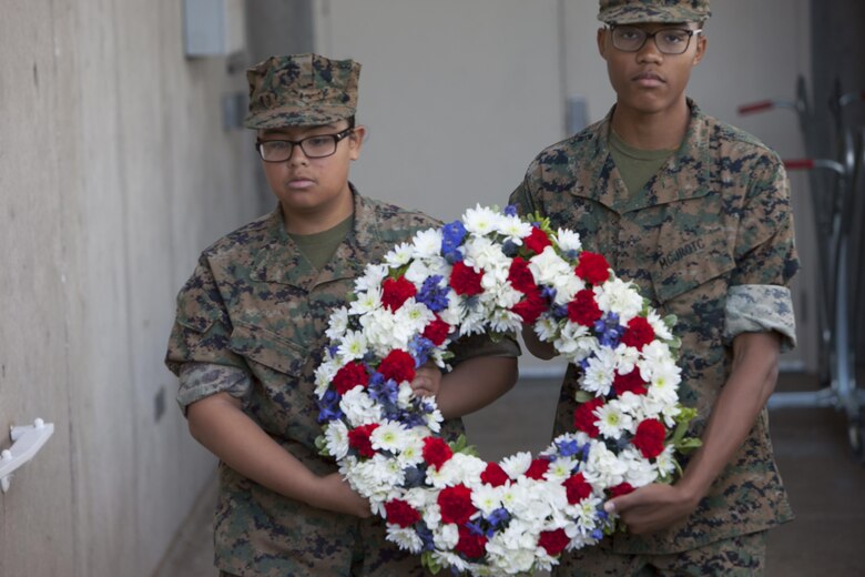Basic High School Marine Corps Junior ROTC cadets carry a wreath to be placed in front of a Veterans Deceased Panel with the names inscribed of all deceased service members that resided in Henderson, Nev. during the city’s Veterans Day celebration, Nov. 5.  All attendees walked to the Veterans Memorial Wall to join in the celebration. (U.S. Air Force photo by Lawrence Crespo)