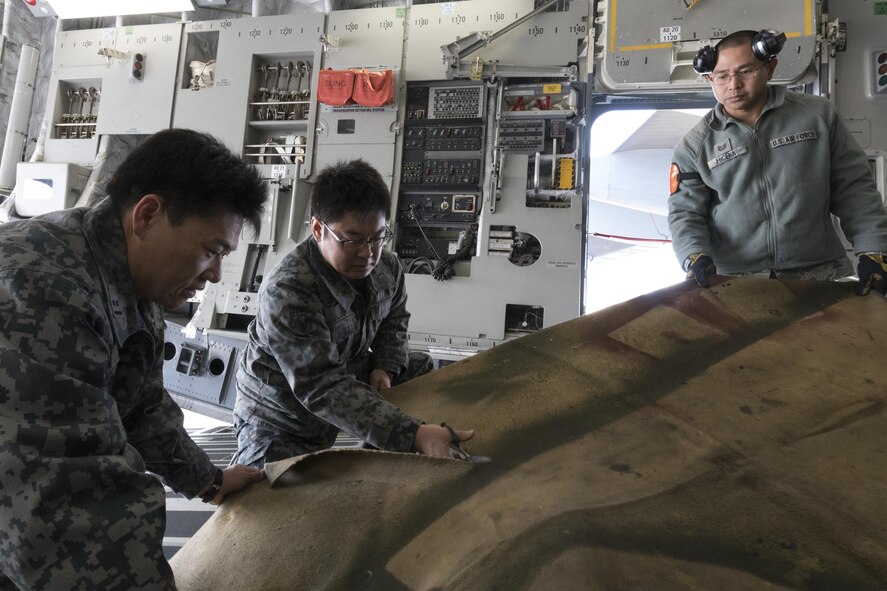 (Center) Japan Air Self-Defense Force Staff Sgt. Tomohiro Kohama, 10th Fire Unit, cuts a blanket at Yokota Air Base, Japan, Nov. 6, 2016, during the exercise Keen Sword 2017. JASDF members from the 3rd Air Defense Missile Group 10th Fire Unit loaded an Electric Power Plant vehicle onto a U.S. Air Force C-17 Globemaster III at first time. Units from the U.S. military conduct training with Japan Self-Defense Forces counterparts at military installations throughout Japan, the Mariana Islands and in the surrounding waters. All participating units train in a comprehensive scenario that is designed to practice the critical capabilities and interoperability required to support the defense of Japan, and to respond to a potential crisis or contingency in the Indo-Asia-Pacific region. (U.S. Air Force photo by Yasuo Osakabe/Released) 