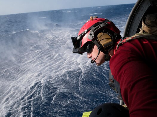 U.S. Air Force Staff Sgt. Adam Lopez, assigned to the 31st Rescue Squadron (RQS) as a pararescueman, scans the ocean during a training flight on an HH-60G Pave Hawk helicopter assigned to the 33rd RQS, Nov. 4, 2016,  near Okinawa, Japan. During the training, members of the 33rd RQS practiced recovery operations for a simulated downed pilot in a hostile environment. (U.S. Air Force photo by Senior Airman John Linzmeier)