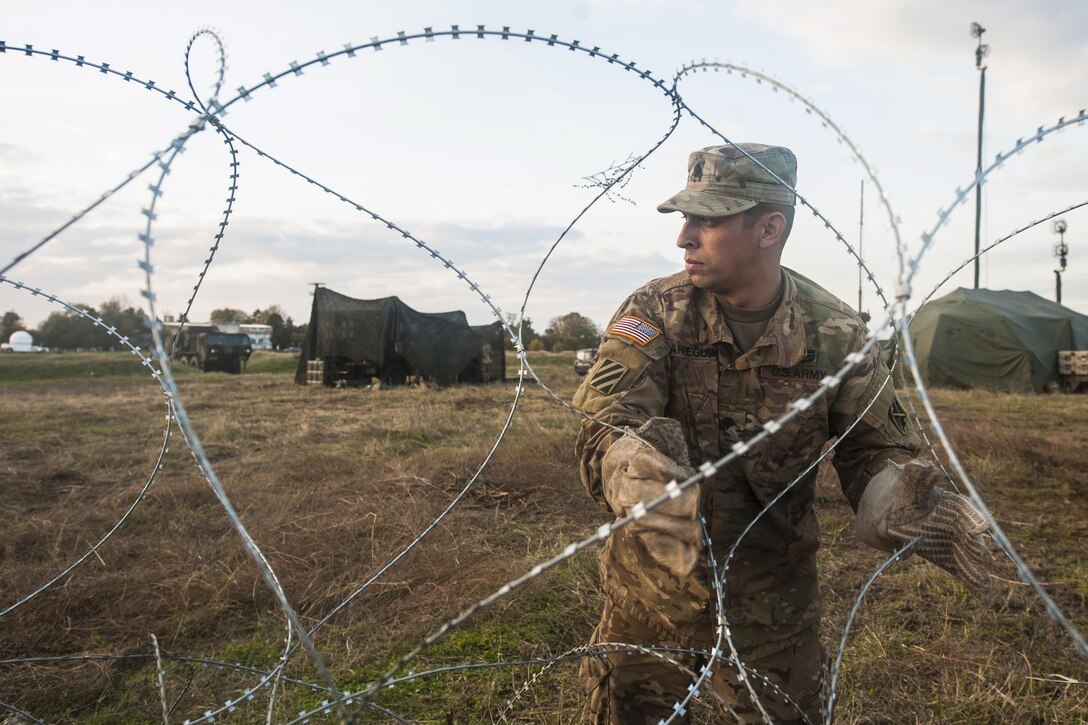 Army Spc. Guadalupe Arreguin places razor wire to create an entry control point during Patriot Shock, a weeklong exercise in Capu Midia, Romania, Nov. 4, 2016. The exercise tests the unit’s quick readiness to respond quickly and increases joint interoperability with Patriot missile systems and their Romanian partners. Arreguin is assigned to the 5th Battalion, 7th Air Defense Artillery Regiment. Air Force photo by Tech. Sgt. Brian Kimball