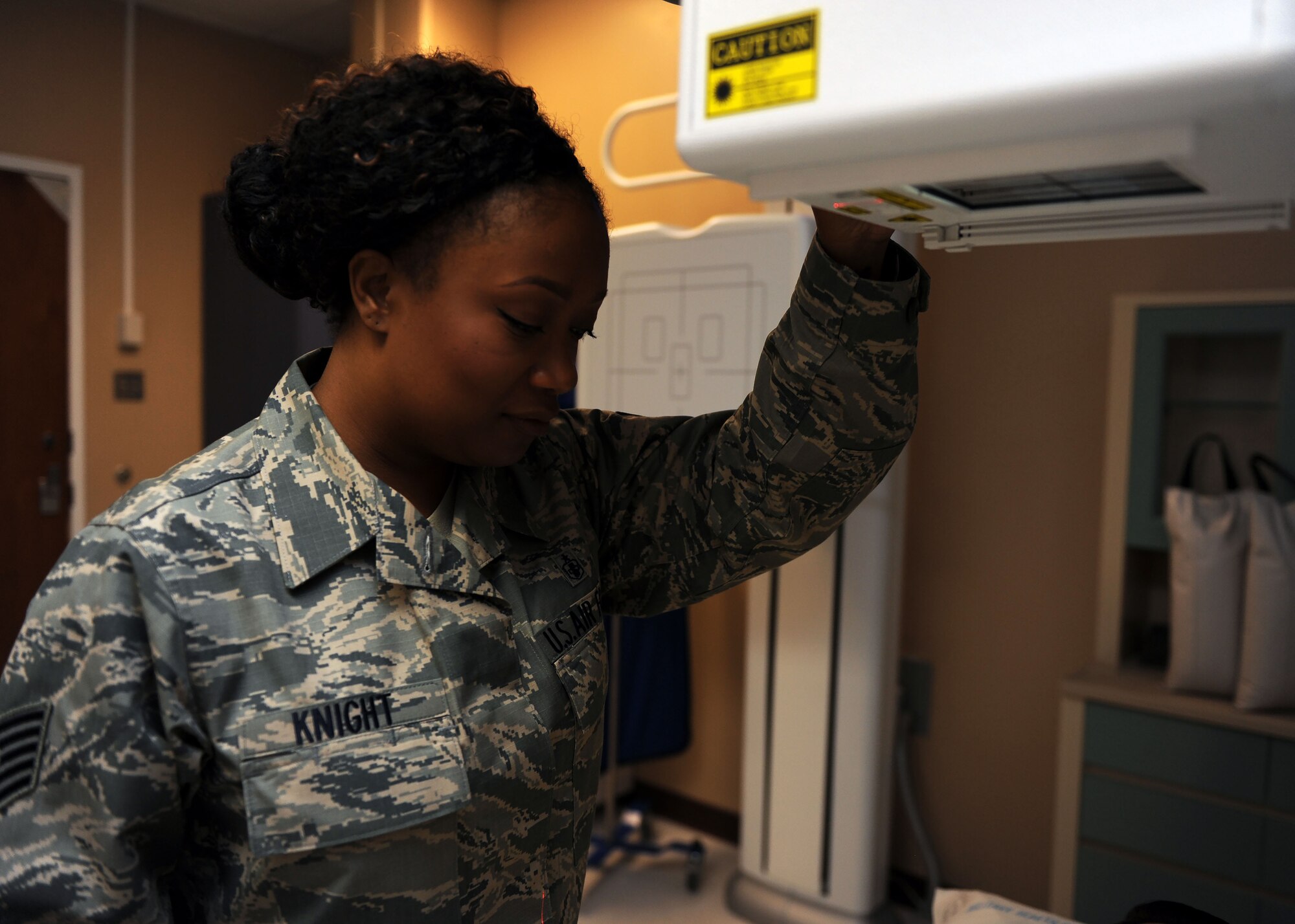 Tech. Sgt. Anissa Knight, 27th Special Operations Medical Support Squadron NCO-in charge of diagnostic imaging, simulates proper X-ray equipment positioning at 27th Special Operations Medical Group, Oct. 25, 2016. Diagnostic imaging technologists assist physicians by taking comprehensive X-rays of afflicted body parts in settings ranging from surgery centers to imaging rooms. These professionals utilize highly sophisticated equipment and an intimate knowledge of human anatomy to help generate reliable imagery and treat their patients. (U.S. Air Force photo/Staff Sgt. Whitney Amstutz/released)